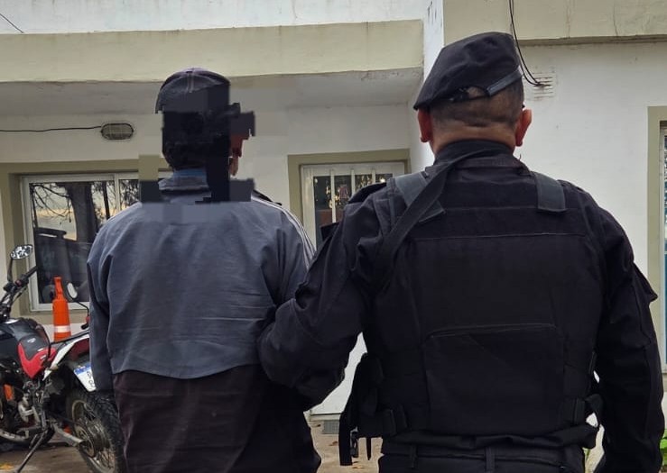 Un policía escolta al detenido a la Comisaría 19na. de Sauce Viejo.