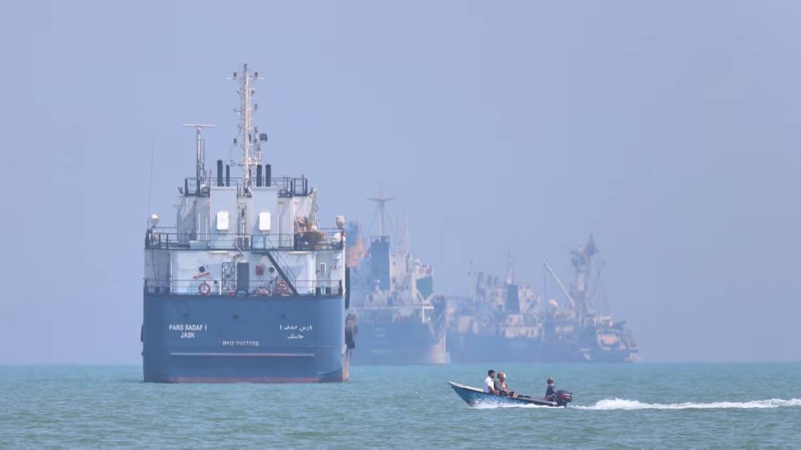 Un pequeño bote pasa frente a embarcaciones ancladas en el estrecho de Ormuz, frente a Bandar Abbas, Irán (Foto: AP/ISNA/Amirhosein Khorgooi).